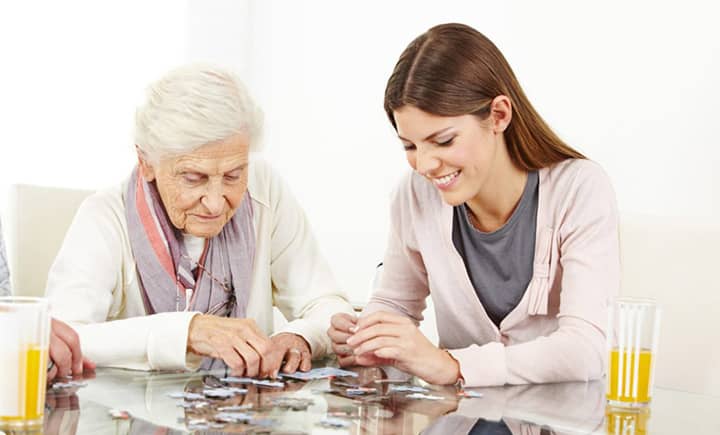 Elderly mother and granddaughter working on a puzzle