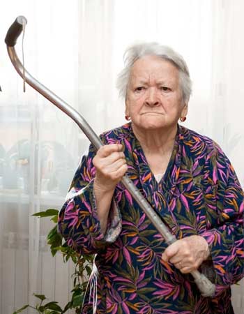 Elderly lady holding up her cane in an aggressive manner
