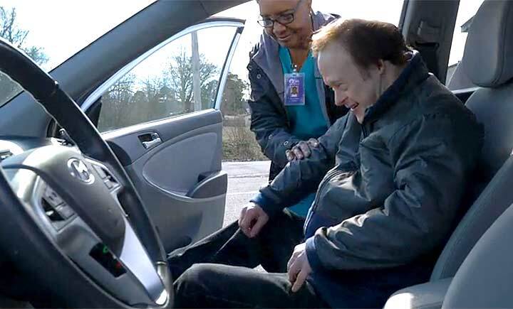 Caregiver using ramp to load client in wheelchair into vehicle