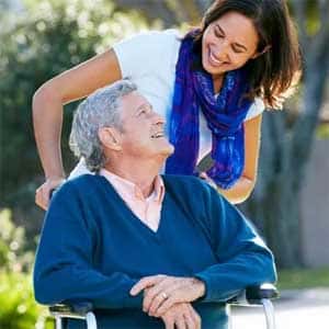 Caregiver pushing a client in a wheelchair outdoors