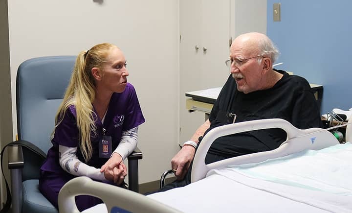 Caregiver sitting with client in hospital room