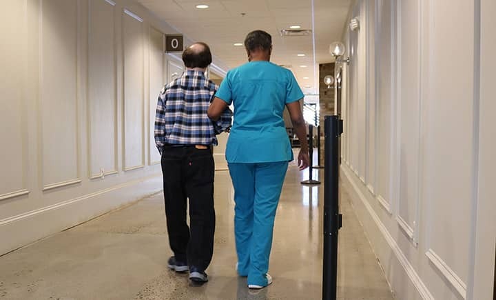 Caregiver walking arm in arm with client as they are leaving a facility